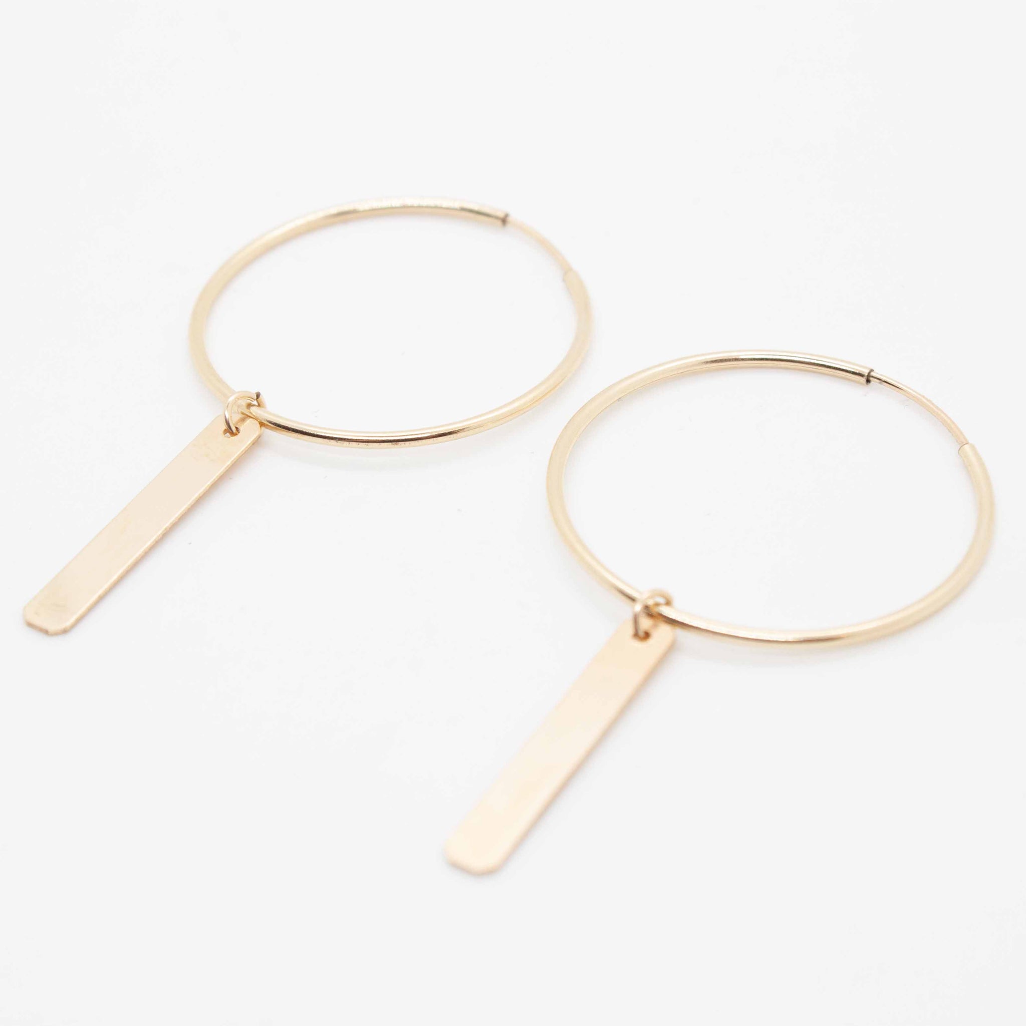 A sleek and sophisticated take on your everyday gold hoop, these are some sexy beasts.  30mm gold filled hoop earrings with gold tag charms. Made in Toronto.
